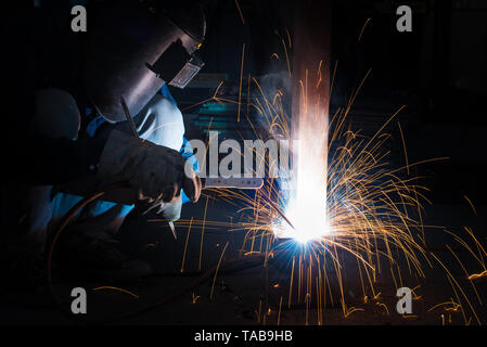 Welding skills training of welder with protective mask and welding steel metal part. Stock Photo