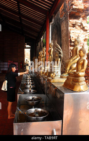 Ayutthaya, Thailand - April 29, 2014. Woman in Buddhist temple offering coins by placing them in Monk's Bowls. Stock Photo