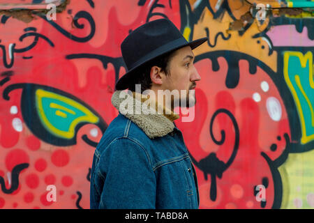 Portrait of a stylish handsome young man with a denim wool jacket outdoors.  A man wearing a denim wool jacket and a hat. Stock Photo