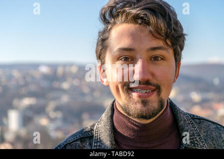 Portrait of a handsome young man with braces outdoors.  A man with braces smiling at the camera. Stock Photo