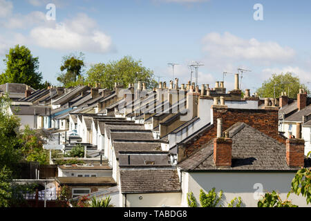 A view of the roof tops of a gently curving street of older Victorian terraced houses with chimneys and television aerials. Stock Photo