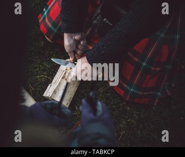 Closeup of man cutting wood shavings with a knife. Stock Photo
