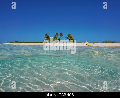 Tropical island sandy sea shore with a kayak on the beach and sand underwater, French Polynesia, Pacific ocean, split view half over and under water