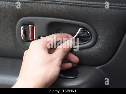 Hand on the inside car handle / Man hands to open door pressing button locking doors in car Stock Photo