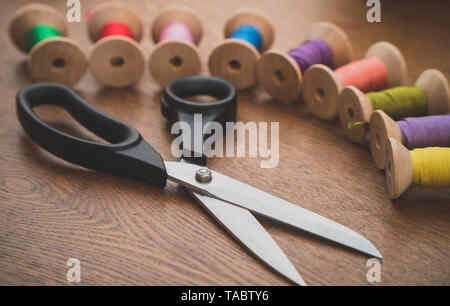 Sewing concept. Scissors and colorful thread spools. Stock Photo