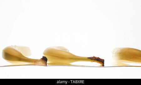 Closeup photo of fresh ripe yellow bananas falling and splashing in clear water against isolated white backgorund Stock Photo