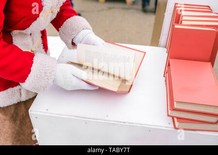 The girl is holding a book in her hands. Opened book in the cancers of the woman. Book spread with pages. A student is leafing through a book. A stack Stock Photo