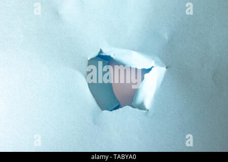 hole torn in blue paper on white background as pattern Stock Photo