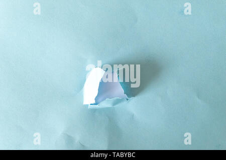 hole torn in blue paper on white background as pattern Stock Photo