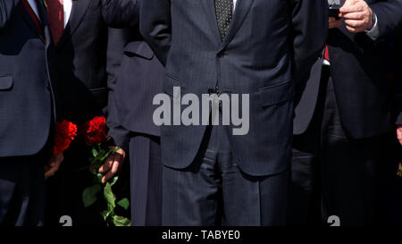 Men in strict black suits with red flowers. Company management. The official delegation. Without a face. Stock Photo