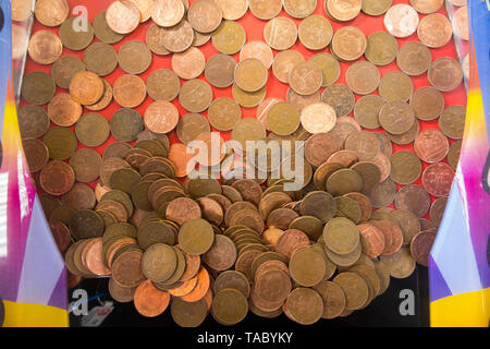 Two pence 2p coins waiting to fall and be won ( or lost and go to the arcade proprietor ) in a traditional coin pusher / pushing coins game at a (99 Stock Photo