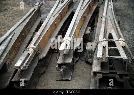 Old dismounted swivel tram rails lie on the asphalt. Roads and urban economy. Daylight. Scrap metal Stock Photo