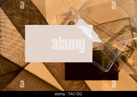 Blank business cards on transparent box, and direct light forming geometric shadows Stock Photo