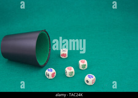 Close-up of a beaker with poker dice on a green game table Stock Photo