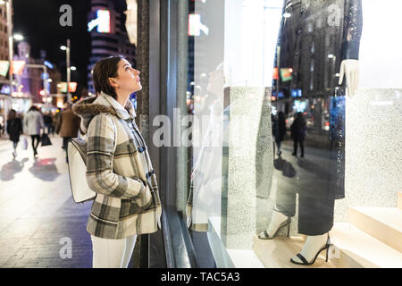 Spain, Madrid, young woman in the city at night next to Gran Via looking at a window shop Stock Photo