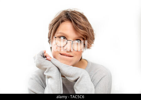 Portrait of thinking young woman with glasses and wireless earphones Stock Photo