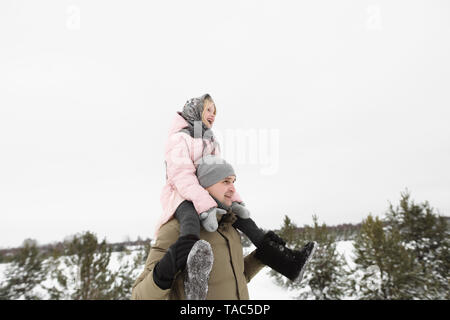 Father carrying little daughter on his shoulders in winter Stock Photo