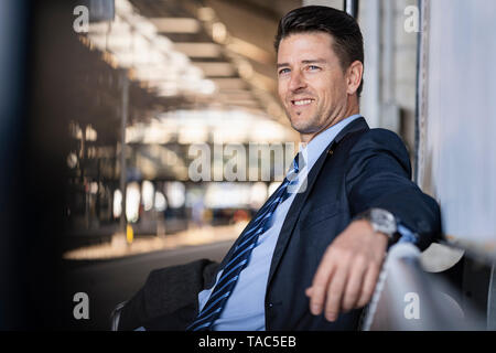 Smiling businessman waiting on station platform Stock Photo