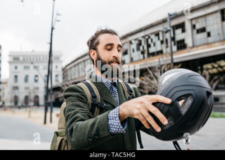 Portrait of man putting on bicycle helmet in the city Stock Photo