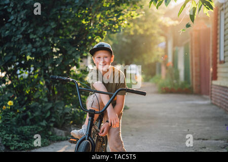 Portrait of smiling boy with bmx bike on road Stock Photo