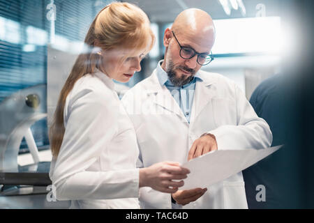 Two technicians wearing lab coats looking at plan Stock Photo