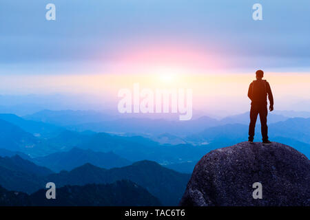 Young happy backpacker on top of a mountain enjoying valley view Stock Photo