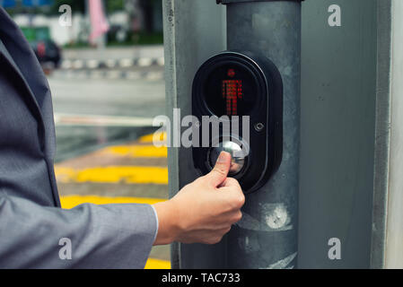 businessman hand pressing pedestrian crossing light button Stock Photo