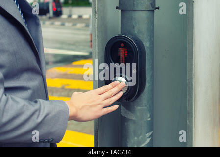 businessman hand pressing pedestrian crossing light button Stock Photo