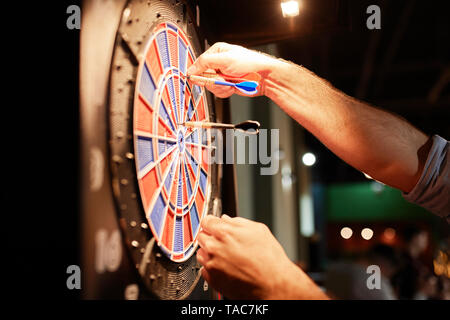 Close-up of man taking out darts from electronic dartboard Stock Photo
