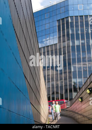 View from the Eastern exit of Old Street Underground Station. Tiled walls with handrails, two people walking down, and a modern building are seen. Stock Photo