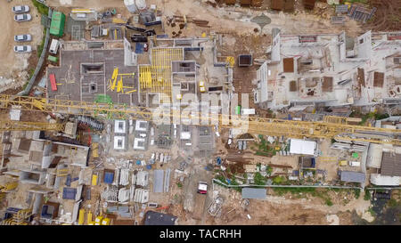 Construction site - Aerial image of a large Residential compound during early stages of construction, with cranes and green surrounding environment. Stock Photo