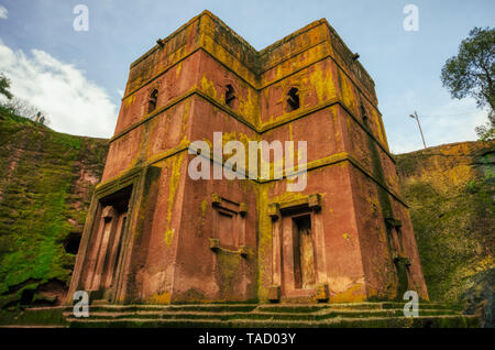 The churches of Lalibela excavated excavated in the bedrock with the cross of San Jorge. The incident light reflects the ocher, yellow and green chara Stock Photo