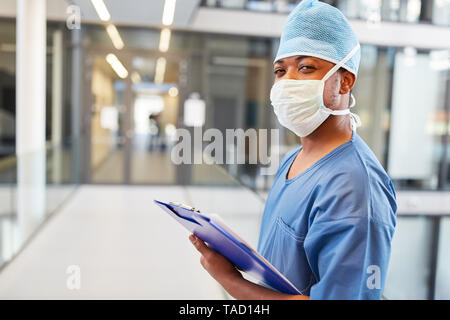 African doctor in blue surgical gown and with clipboard in front of the emergency room Stock Photo