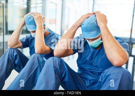 Two exhausted surgeons with hands on their heads as a sign of congestion Stock Photo