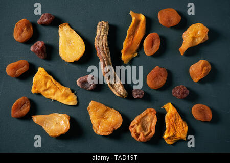 high angle view of an assortment of different dried fruit, such as pear, peach, banana, strawberry, apple or apricot, on a rustic dark gray wooden tab Stock Photo