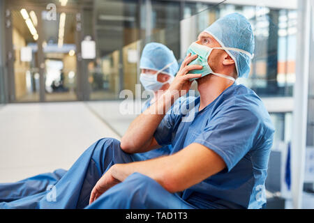 Two exhausted surgeons at the emergency room as a sign of stress and overwork Stock Photo