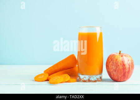 Fresh carrot and apple juice in a glass on a wooden blue background. Selective focus. Copy space. Stock Photo