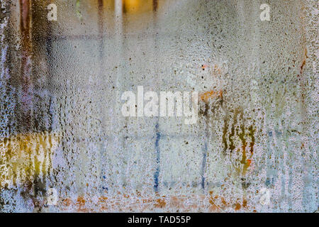 Water droplets on window glass. An iron grille for protection is visible behind the glass. Abstract image. Stock Photo