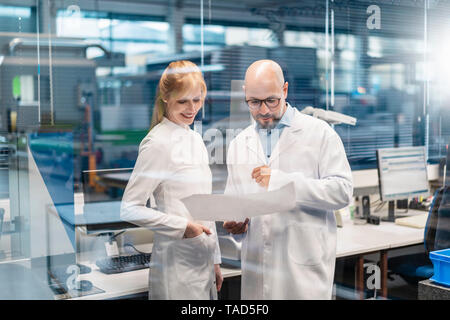 Two technicians wearing lab coats looking at plan Stock Photo