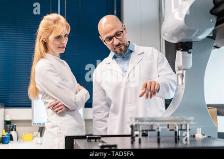 Two technicians wearing lab coats standing at machine Stock Photo