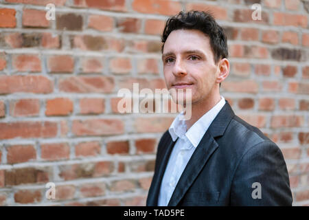 Portrait of confident businessman at brick wall Stock Photo