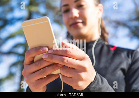 Close-up of young woman training and checking her smartphone Stock Photo