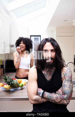 Portrait of smiling tattooed man with girlfriend in kitchen Stock Photo