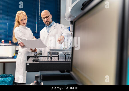 Two technicians wearing lab coats looking at plan Stock Photo
