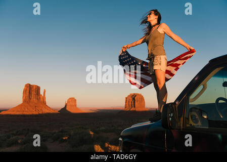 USA, Utah, Monument Valley, Woman with United States of America flag enjoying the sunset in Monument Valley Stock Photo