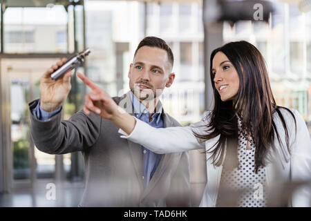 Businessman and businesswoman examining workpiece in factory Stock Photo