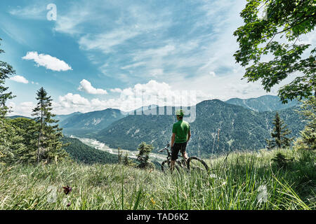 Germany, Bavaria, Isar Valley, Karwendel Mountains, mountainbiker on a trip having a break on alpine meadow Stock Photo