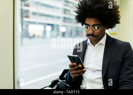 Spain, Barcelona, businessman in a tram using cell phone Stock Photo