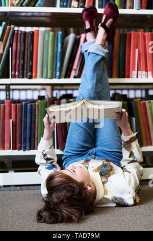 Female student reading book in a public library Stock Photo