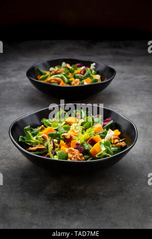 Two bowls of mixed green salad with hokkaido pumpkin and walnuts Stock Photo